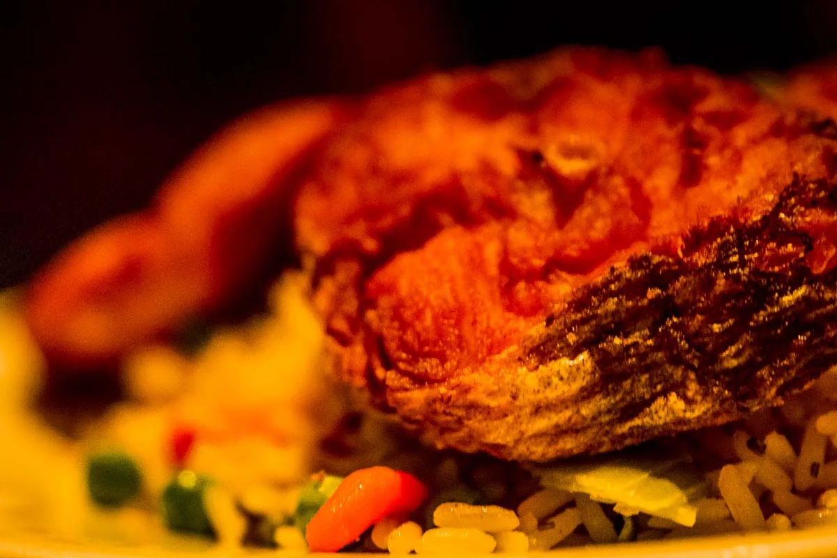 Close-up of fried chicken on fried rice with peas and carrots