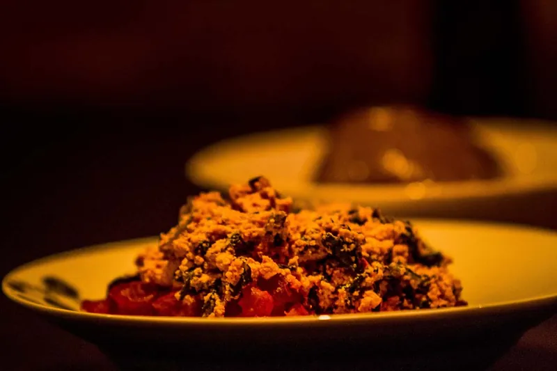 A plate of vegetable stew, with a covered dish behind it