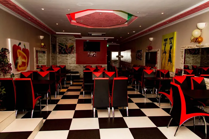 The length of the dining room: chequered floor, red and black chairs, and a red feature wall at the back